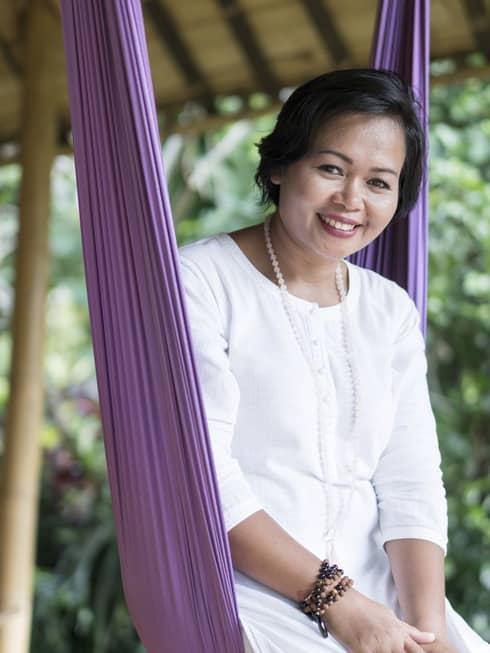 A smiling wellness expert sitting up in a hammock