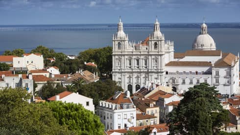 White cathedrals, houses and rooftops in Lisbon, ocean in background
