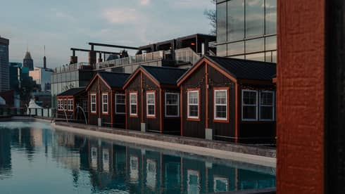 Four cottages with orange trimming beside a pool and city buildings