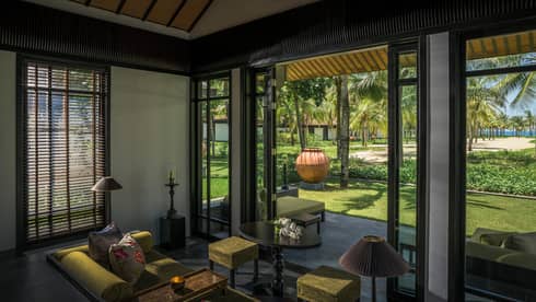 Pool Villa living room with green velvet sofa, stool, high ceilings, open patio wall