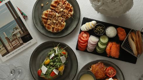 An assortment of food, including vegetables, salad and waffles on black plates.