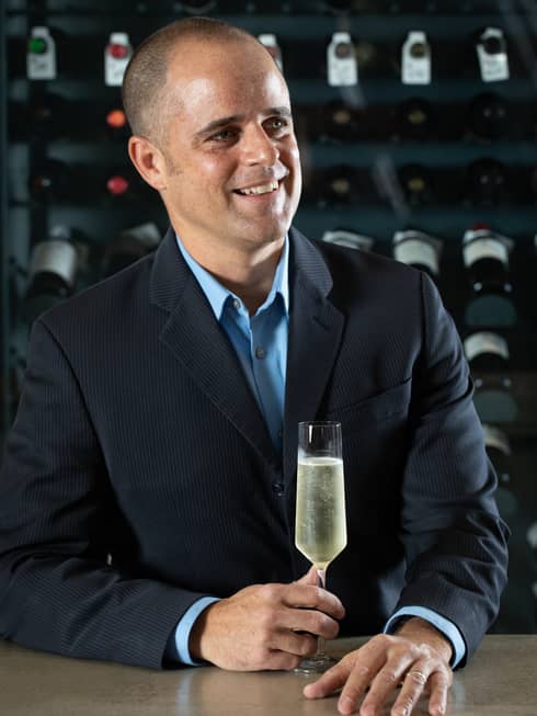 A man in a suit holding a glass of Champagne.