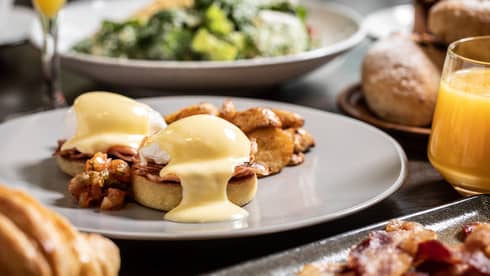 Sunday brunch table with Eggs Benedict, bacon and salad 