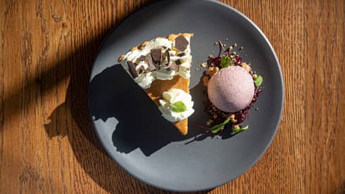 Pumpkin pie and scoop of ice cream on a dark grey plate