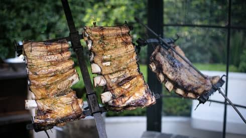 Several racks of ribs roasting over a fire.