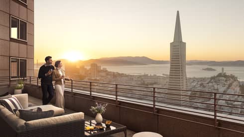 Man and woman take in San Francisco and bay views from private luxury terrace at Four Seasons Hotel San Francisco at Embarcadero