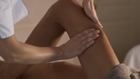 A spa therapist massages a woman's leg