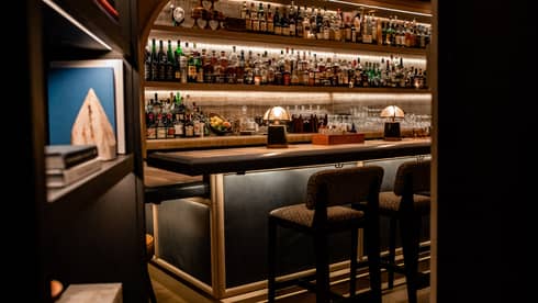 A bar with many bottles of liquor behind a bookcase.