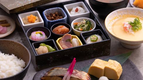 Traditional Japanese bento box breakfast with obanzai side dishes, tamagoyaki (Japanese rolled omelette), congee, steamed rice and miso soup