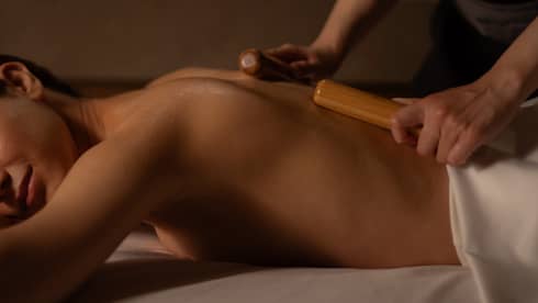 Guest receiving a traditional Japanese massage in Kyoto with bamboo sticks, part of a relaxing full body spa treatment.