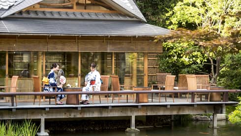 Two women in traditional Japanese garb observing the koi fish swimming below