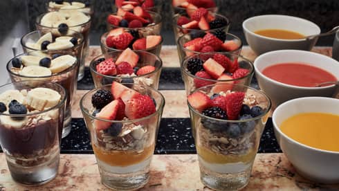 Yogurt and fruit parfait shooters lined up on a brunch buffet display