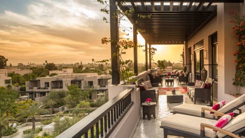 Moorish gardens below below long white hotel balcony with plush patio furniture 