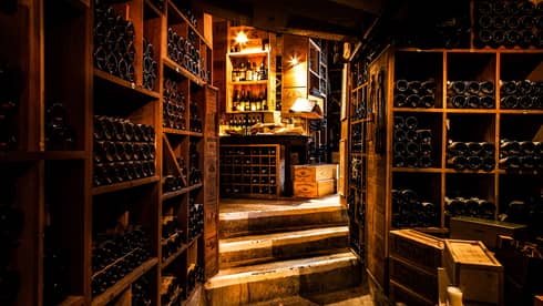 Vintage French wines line walls in dark wood cellar