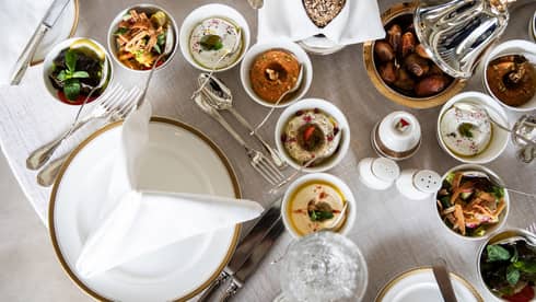 Aerial view of table with assorted Ramadan dishes in silver and ceramic dishes