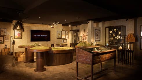 Wide shot of The Great Migration exhibit room with model tables, screen, displays