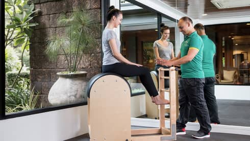 Four Seasons trainer assists woman balancing on pilates beam in Fitness Centre