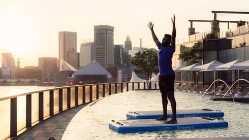 Guest standing in a pool doing pool yoga.