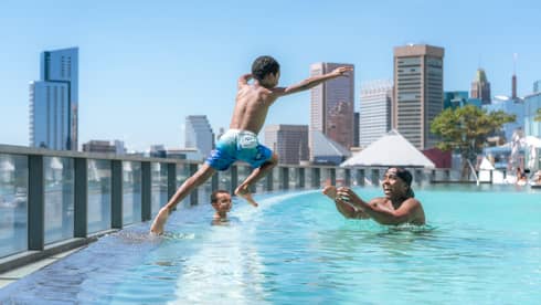 Child jumps into pool as parent waits in the water with open arms