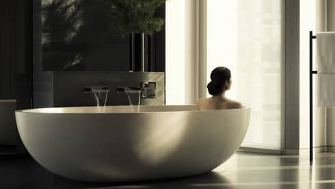 Back of woman soaking in large free-standing tub in spa
