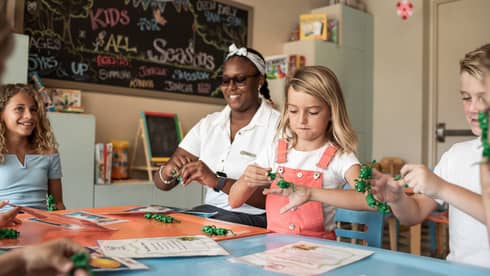 A resort team member doing crafts with young children.