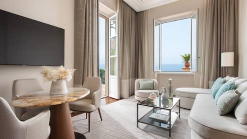 Living room with cream sofa, glass coffee table, dining set and sea-view windows
