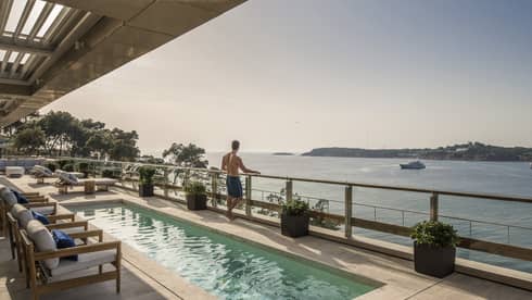 Arion Royal Suite Deck with lap pool and row of lounge chairs, boat on the Mediterranean Sea