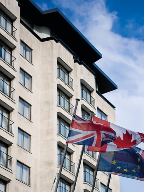 Flags fly against blue sky outside Four Seasons Hotel exterior