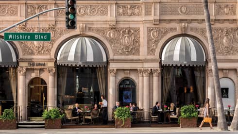 Street-side patio under historic building facade, Wilshire Blvd street sign