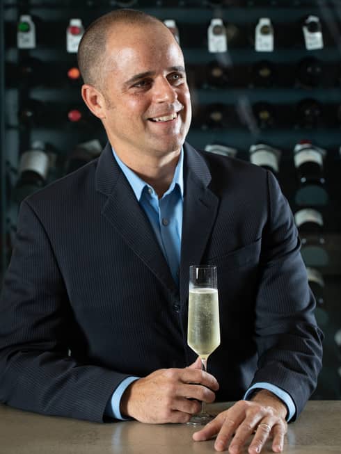 A man in a suit holding a glass of Champagne.