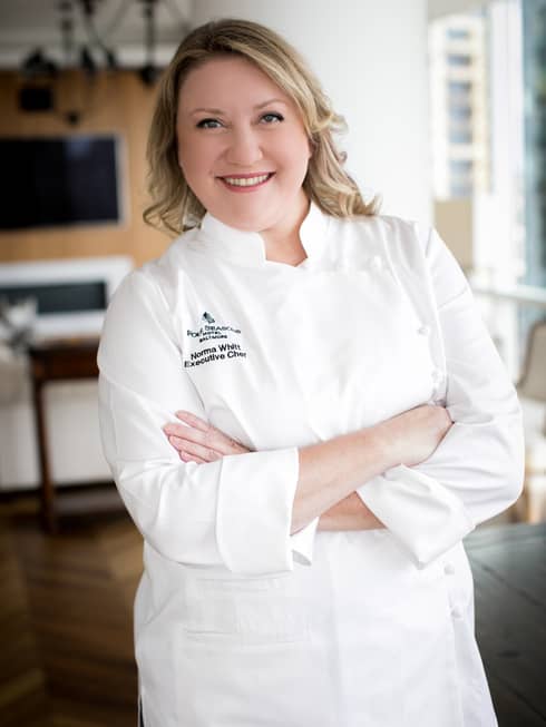 A female chef in white chef clothes crossing her arms.