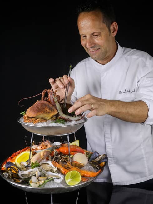 A Four Seasons Chef rearranges a two-tiered seafood display