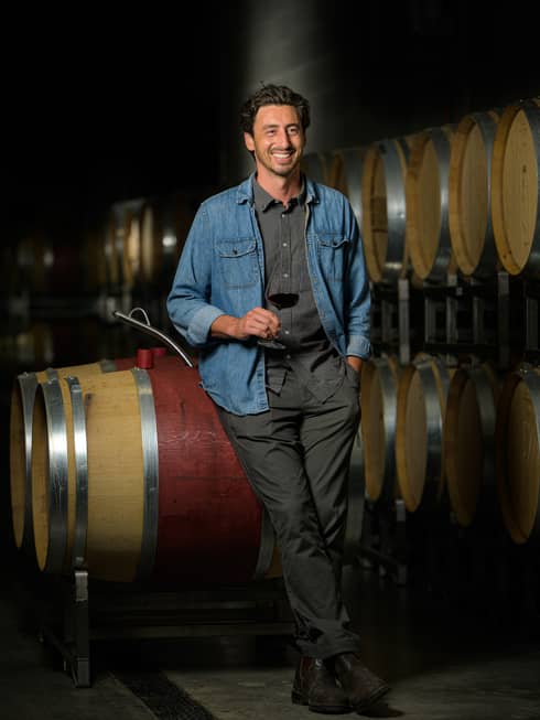 A man in a denim jacket holding a glass of wine.