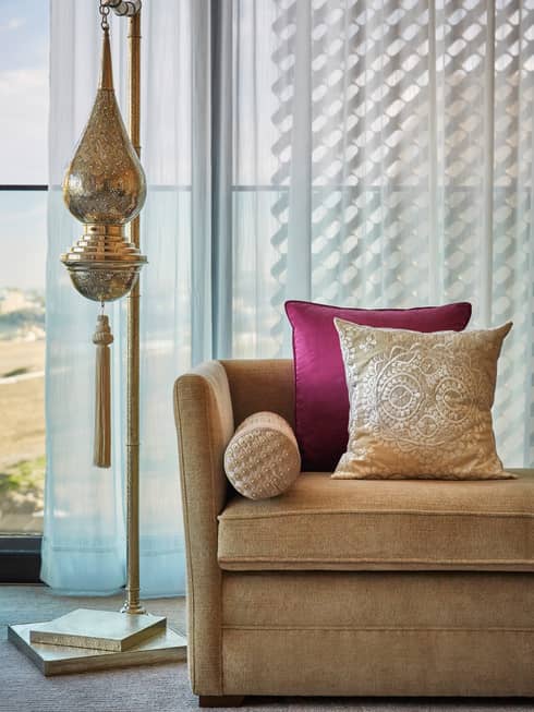 Moroccan lamp, sofa with accent pillows in front of window with white curtains