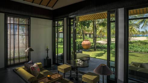 Pool Villa living room with green velvet sofa, stool, high ceilings, open patio wall