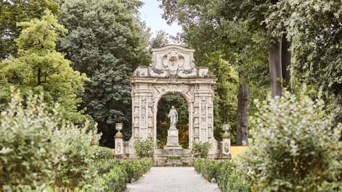 Lush garden with path leading to statue on pedestal