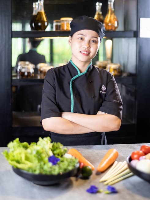 Cooking Academy Chef Trang poses with a bowl of greens and other fresh ingredients