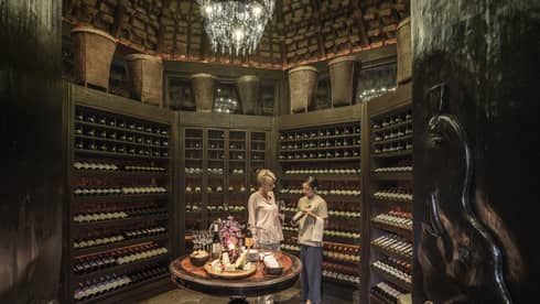 Two people examine wine bottles in Camp Wine Cellar