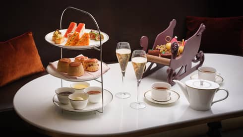 Afternoon Tea three-tiered tray, two glasses of champagne, two cups of tea, and Santa sleigh-looking accessory