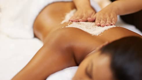 Person receiving a salt scrub back massage at a spa