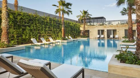 The Moroccan-style pool and lounge framed by thriving greenery and palm trees