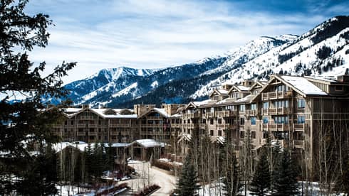 the exterior of the hotel is covered in snow and surrounded by snow capped mountains 