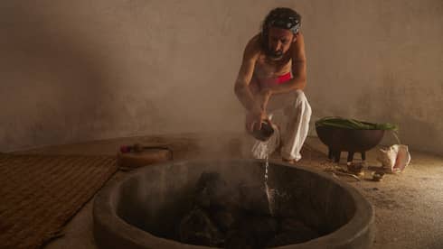 Man tends to a fire in a traditional temezcal or "house of heat"