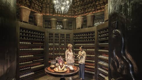 Two people examine wine bottles in Camp Wine Cellar