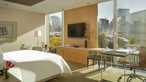 Four Seasons hotel room with a large window, city view, wall-mounted TV and wooden furnishings