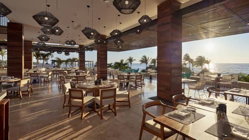 Sun streams into open air dining room with modern wood pillars 
