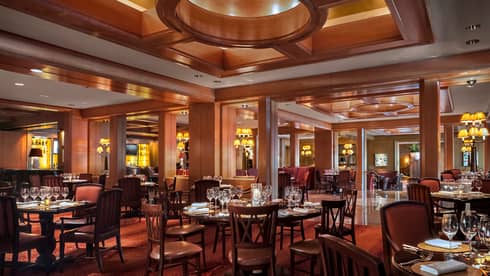 The Bristol elegant dining room with wood tables set with wine glasses and red chairs, high ceilings with wood beams 