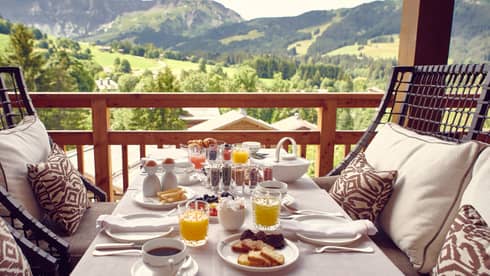 Balcony table with In-Room Dining breakfast set-up overlooking lush greenery and mountains