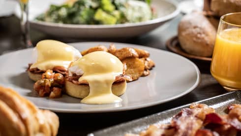Sunday brunch table with Eggs Benedict, bacon and salad 