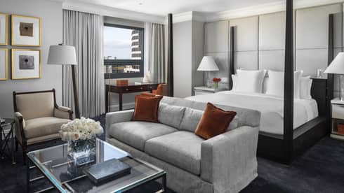 Presidential Suite poster bed against white padded wall, behind seating area 